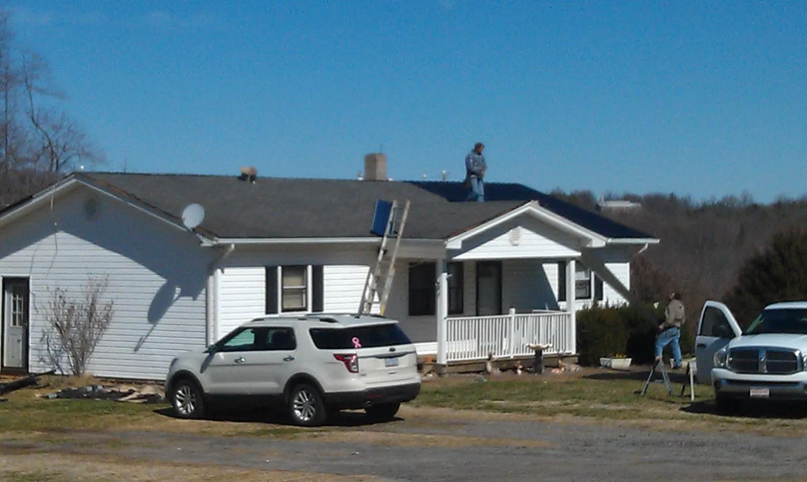 Roofers stripping shingles from a white ranch house roof in Cottonwood